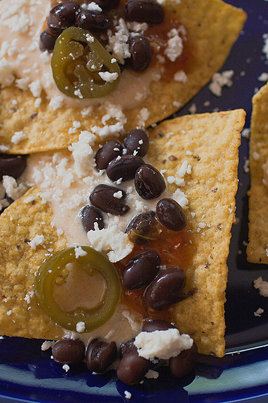 what's black and white and red all over? My white cheese nachos with black beans and salsa rojo. Recipe and photo by Jackie Alpers