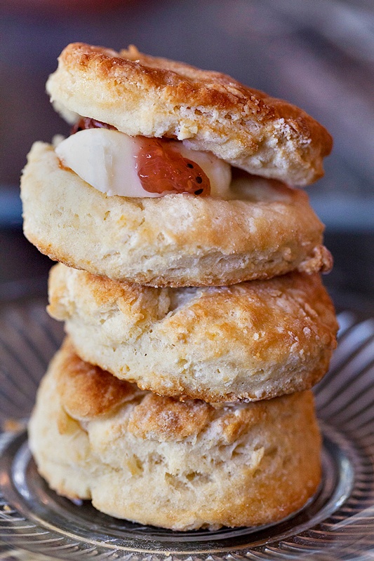 A stack of buttermilk biscuits served with butter and jam