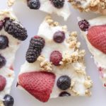 pieces of frozen white yogurt bark with berries and granola on