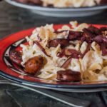 red wine simmered sausages served over a platter of creamy cheesy noodles