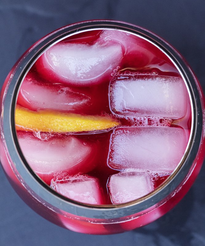 hibiscus aqua fresca in a glass with ice and a orange slice