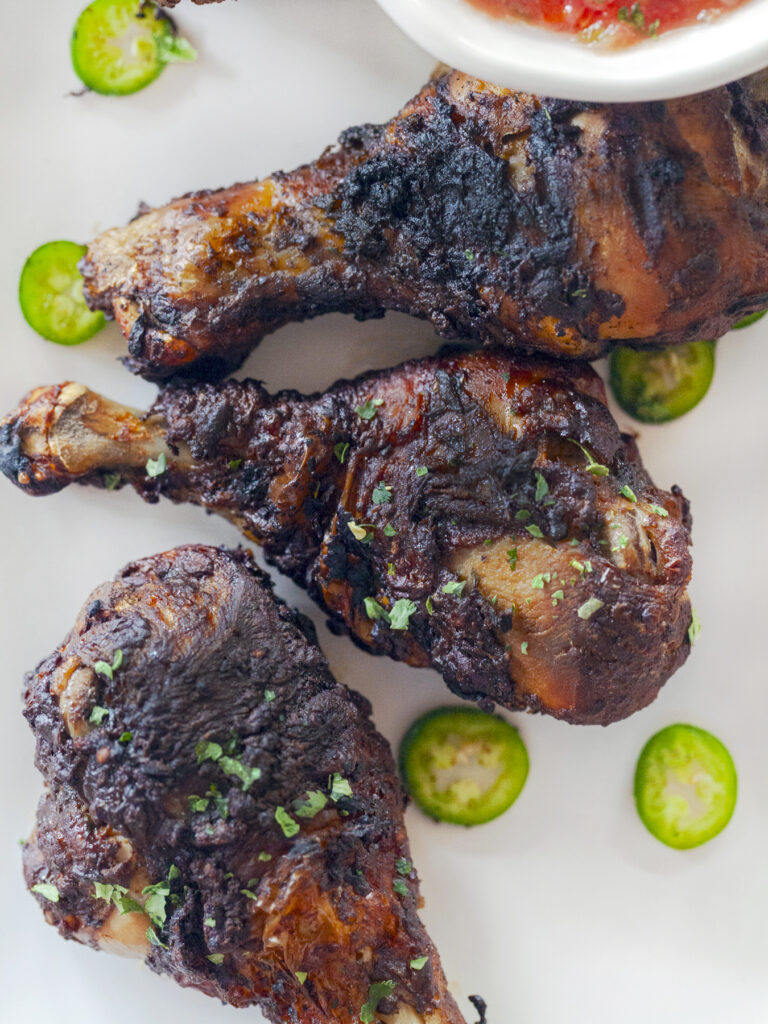 Sonoran style grilled chicken drumsticks with mole marinade on a plate with salsa, recipe and photo by Jackie Alpers