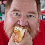 Chef portrait of James Beard award winning chef eating a Sonoran hot dog