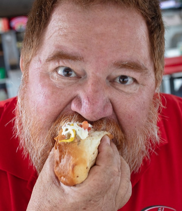 Chef portrait of James Beard award winning chef eating a Sonoran hot dog