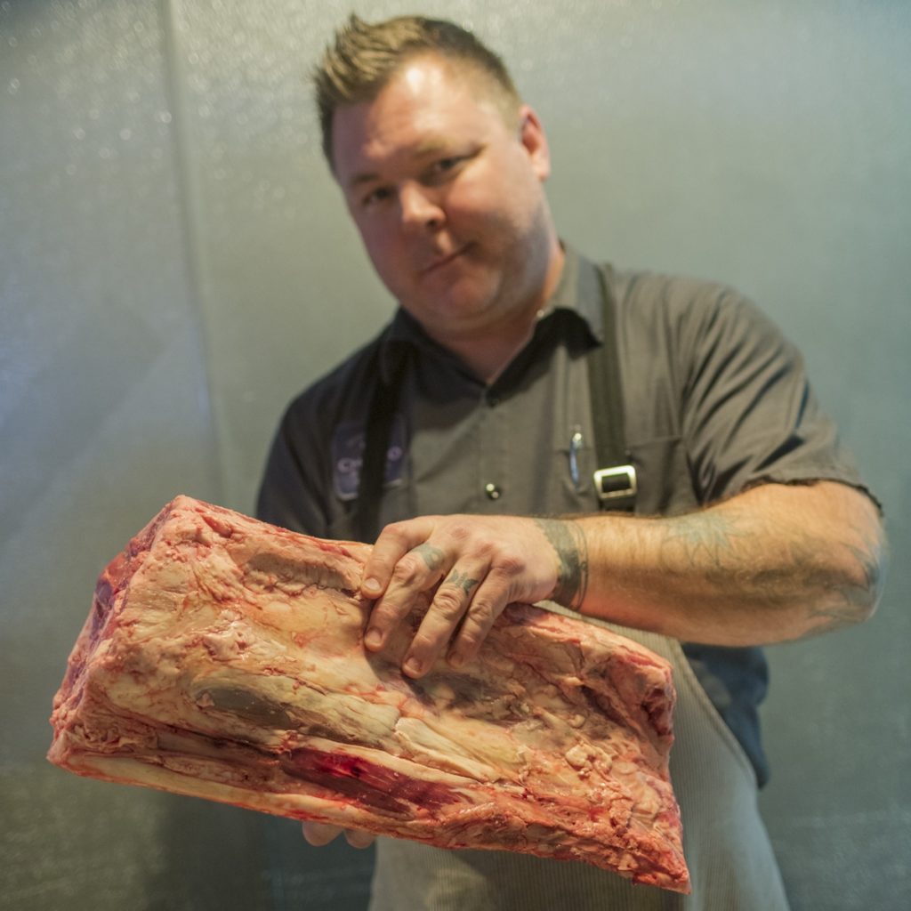 Portrait of chef Gary Hickey holding a slab of meat