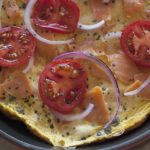 campari tomatoes, lox, red onion and herbs on top of a cream cheese frittata