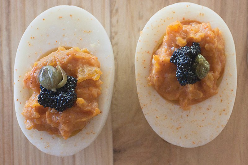 chipotle deviled eggs topped with caviar and capers and sprinkled with chile