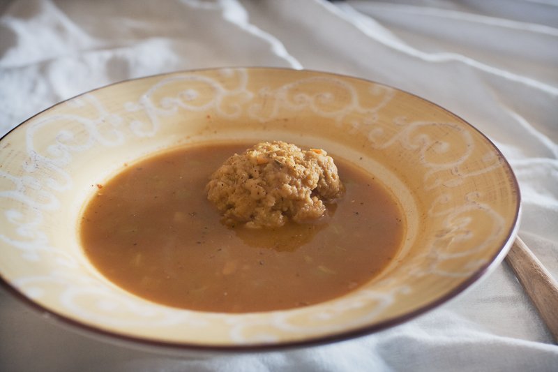 Matzoh ball floating in a bowl of onion barley soup