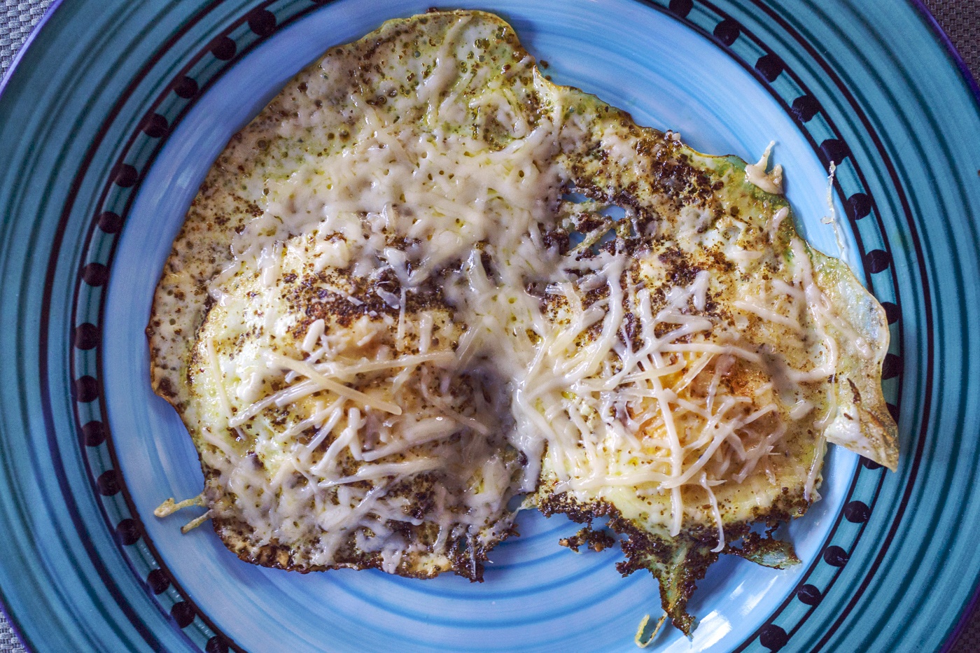 green pesto fried eggs with Parmesan cheese on a blue plate