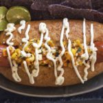 Sonoran Mexican street corn hot dog on a bolillo roll with street corn, mayo and lime.