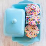 rainbow sprinkles compound butter log cut into rounds on a blue butter dish