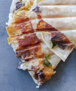 Colorful cheese crusted carne asada quesadillas with crispy cheese on a blue background