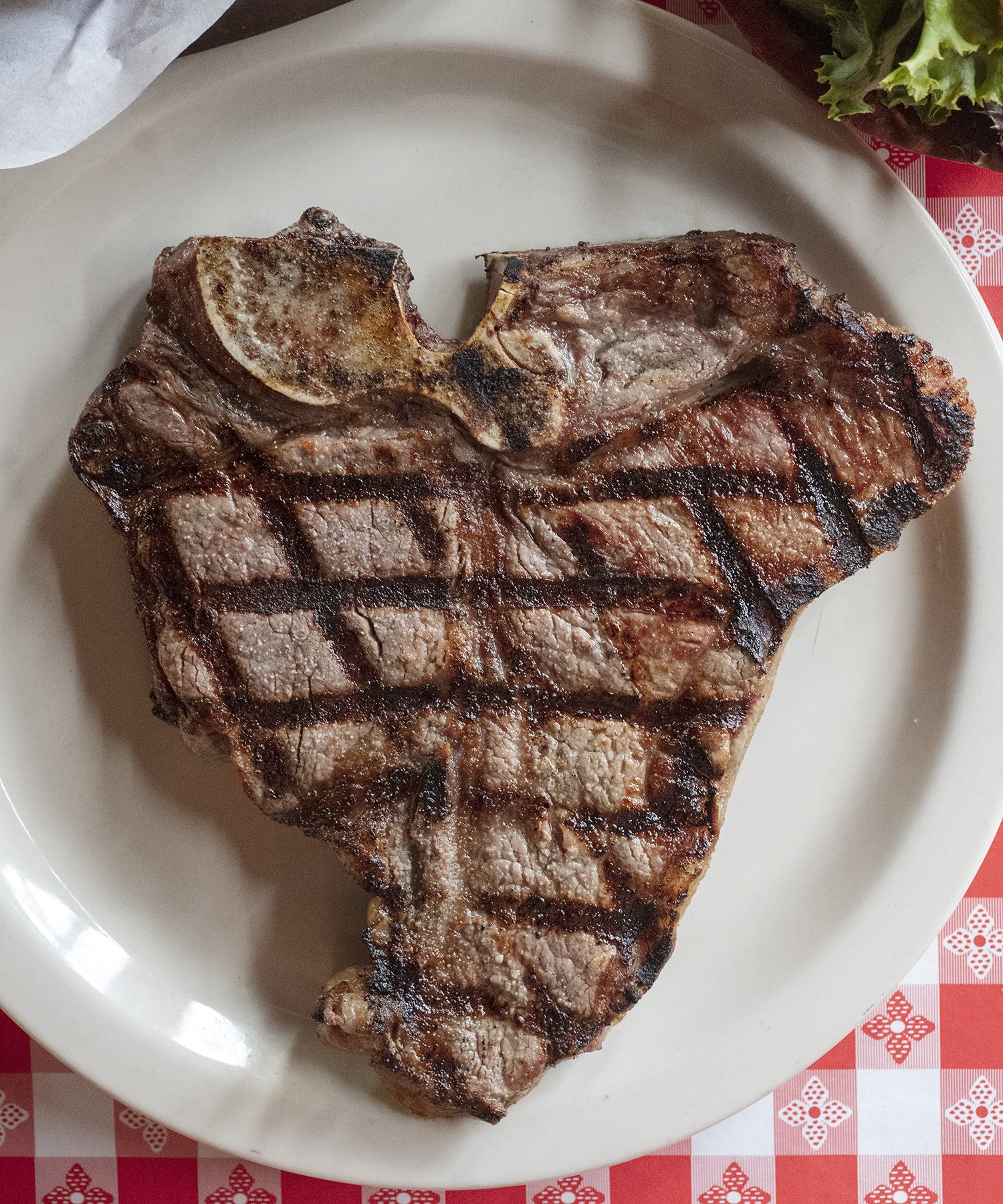 Cowboy Steak with grill marks on picnic table cloth