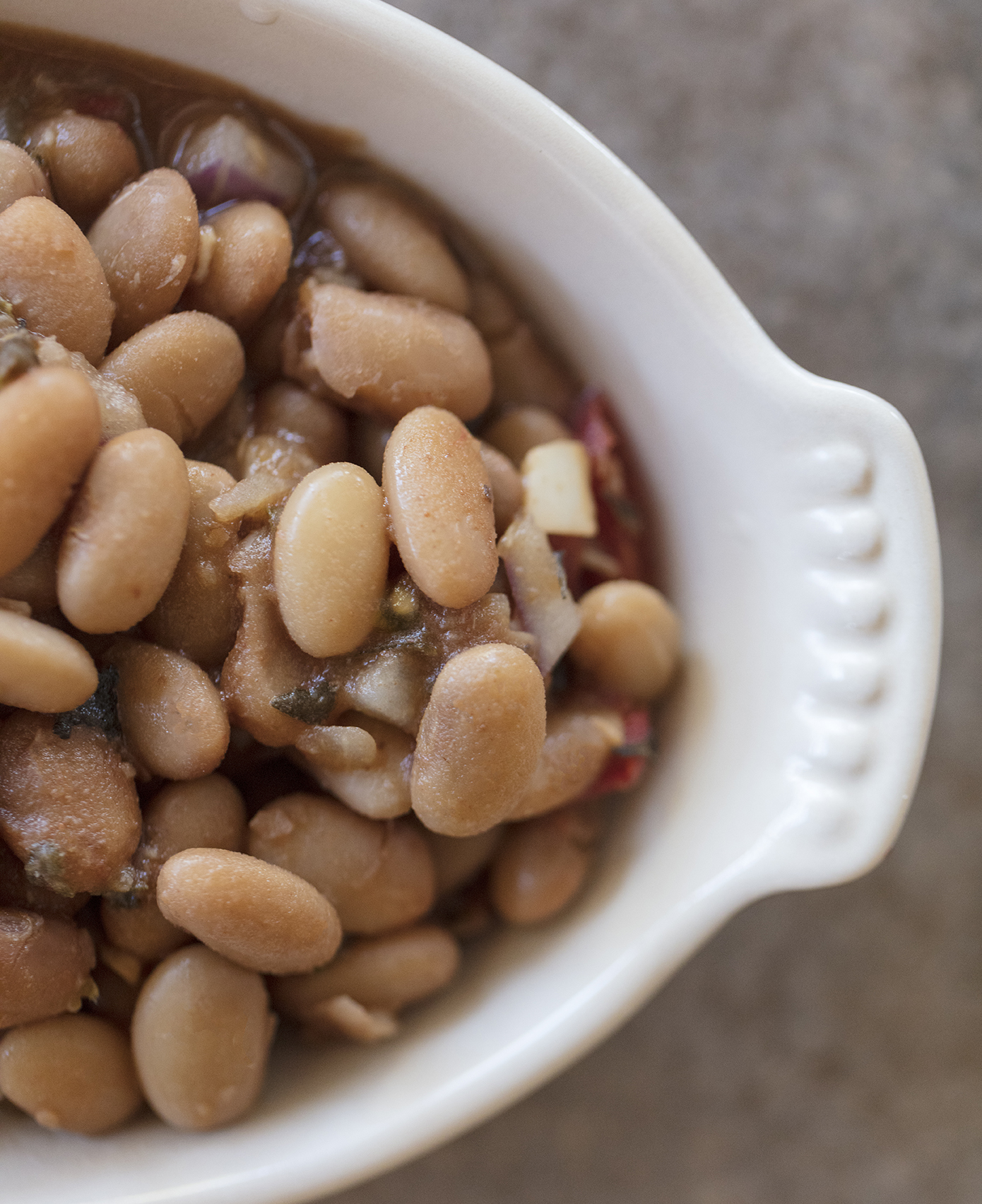 charro cowboy beans in a white side dish. Recipe photo from The Taste of Tucson Cookbook by Jackie Alpers
