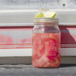 Watermelon moonshine in a bell jar on the back of a pickup truck. Served with lime to cut the burn.