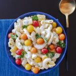 bowl of creamy ranch macaroni salad decorated with tiny tomatoes and sprigs of parsley