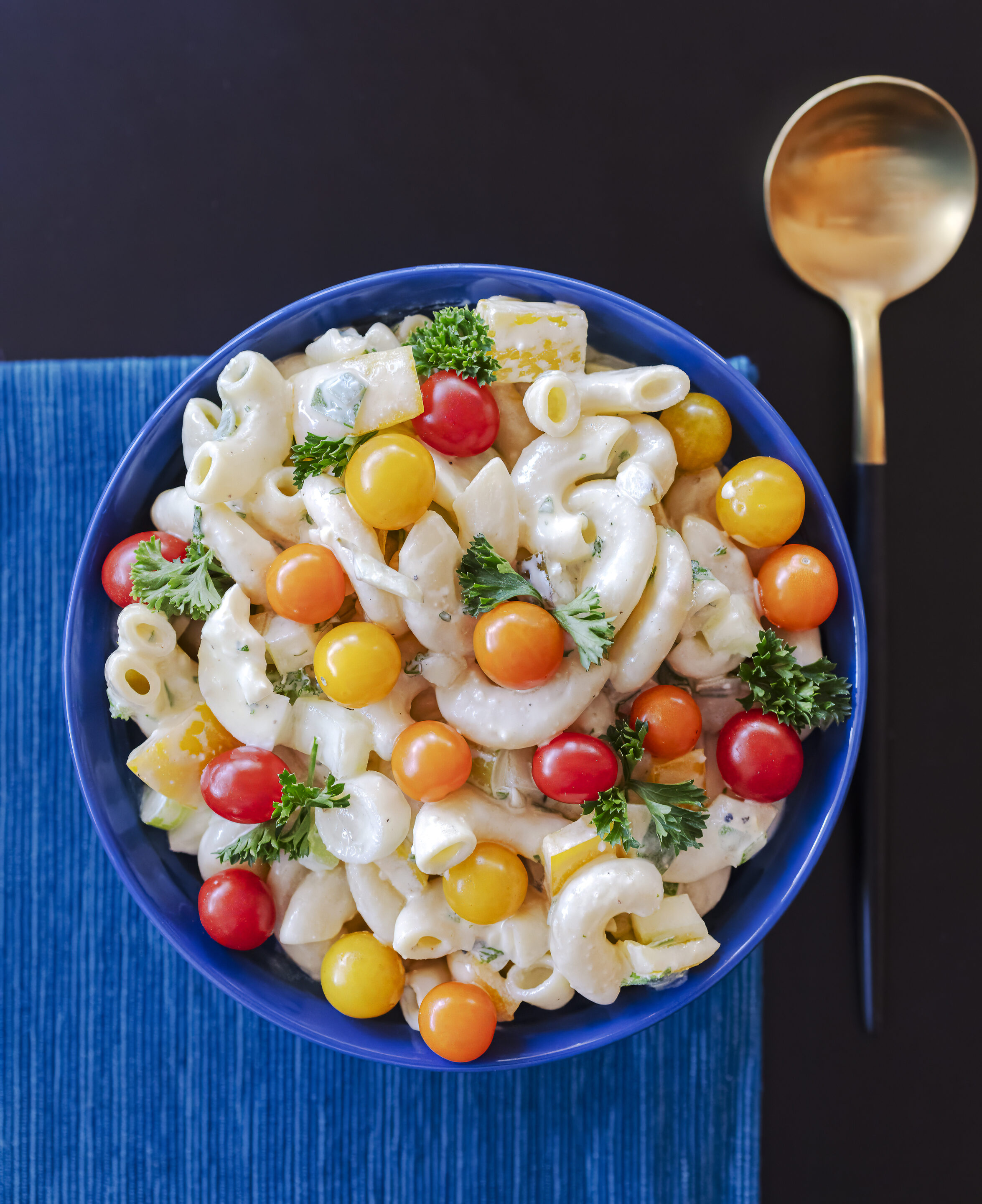 bowl of creamy ranch macaroni salad decorated with tiny tomatoes and sprigs of parsley