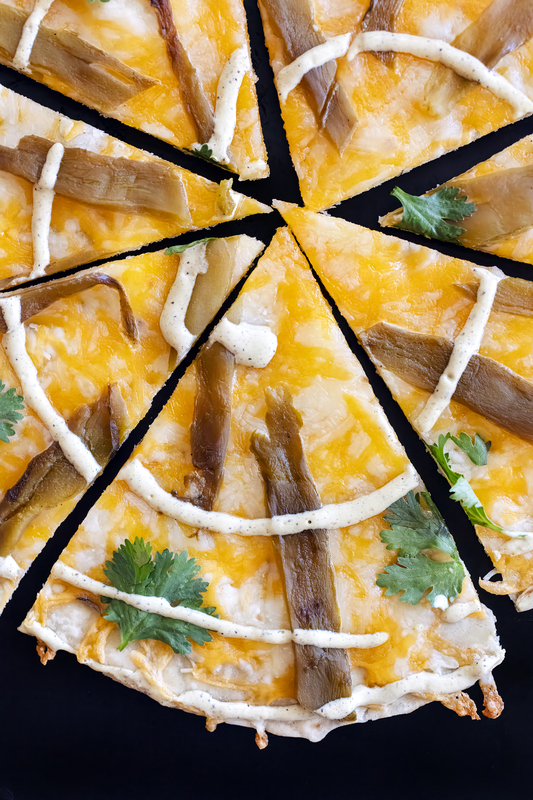 slices of flour tortilla cheese crisp with mexican blend cheese roasted green chile strip, cilantro leaves and ranch spiral.