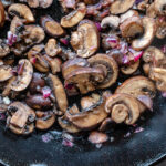 Recipe photography of roasted mushrooms and shallots in a cast iron skillet by Jackie Alpers.