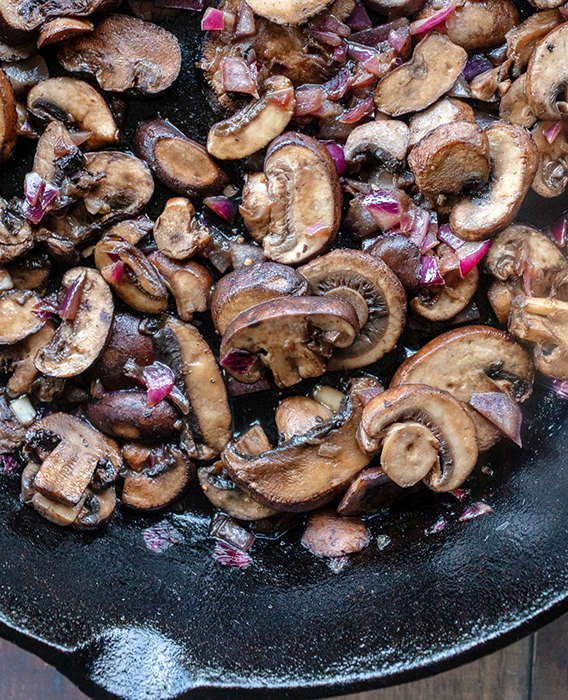 Recipe photography of roasted mushrooms and shallots in a cast iron skillet by Jackie Alpers.