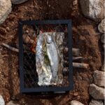 freshwater fish grilling on a camp stove over a wood fire. Recipe and photo by Jackie Alpers.