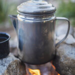 Pot of cowboy coffee brewing over an open campfire with rocks as anchors. Photography and recipe from the Arizona-Mexico borderlands by Sonoran cookbook author Jackie Alpers Jackie Alpers